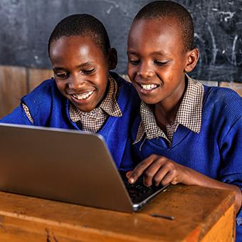 Two school boys in Africa smiling at a laptop